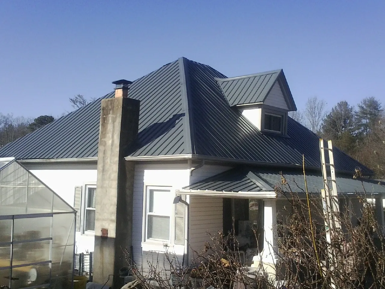Dark blue standing seam metal roof on a white farmhouse with dormer — Slate & Tile Roof Repair by Roofing Brothers in South Salem