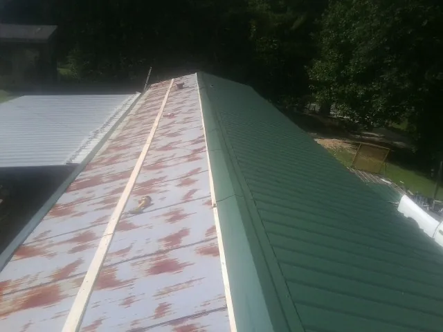 Old rusted panels beside newly installed green metal roofing — Wind Damage Roof Repair by Roofing Brothers in South Salem