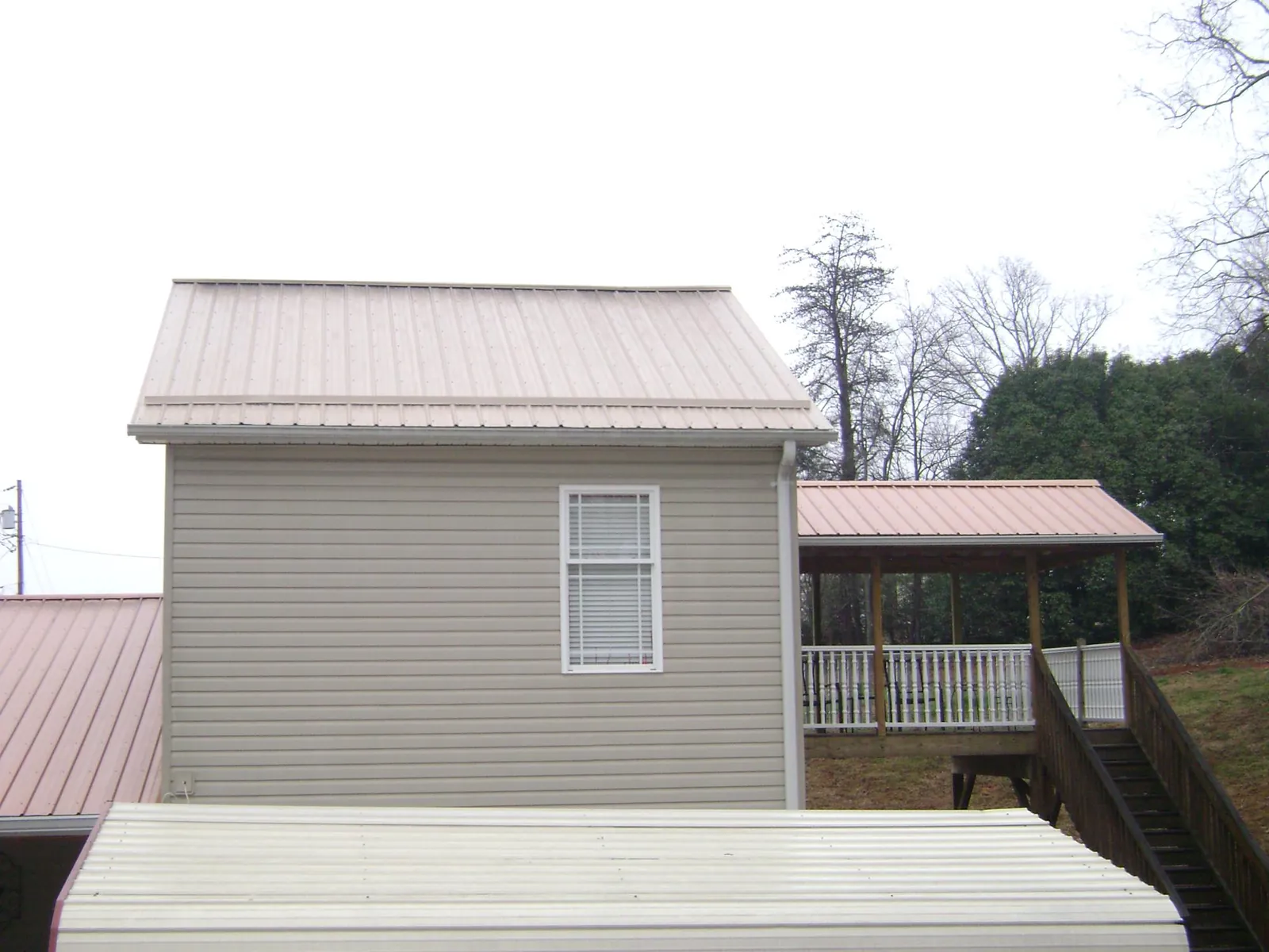 Tan metal roofs on a two story addition and attached porch, from a Roof Replacement job in South Salem
